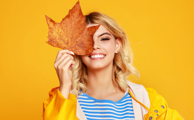 happy emotional girl with autumn leaves on colored yellow background