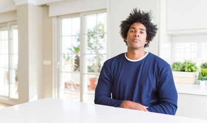 Fototapeta premium Young african american man wearing casual sweater sitting at home Relaxed with serious expression on face. Simple and natural looking at the camera.