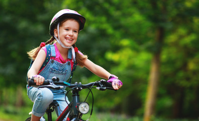 happy cheerful child girl riding a bike in Park in nature.