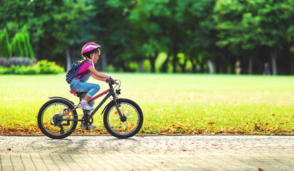 happy cheerful child girl riding a bike in Park in nature. © JenkoAtaman