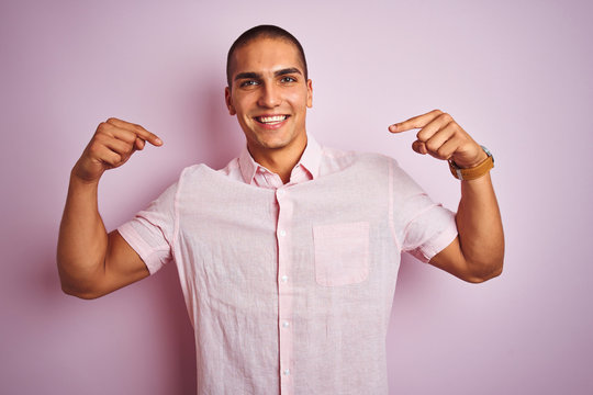 Young handsome man wearing elegant shirt over pink isolated background looking confident with smile on face, pointing oneself with fingers proud and happy.