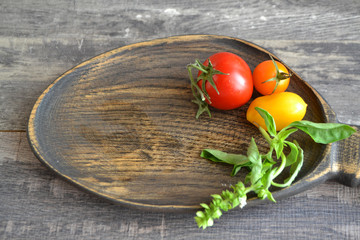 Fresh bright tomatoes on rustic wooden plate, flat lay