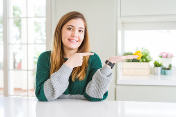Young beautiful plus size woman wearing casual striped sweater amazed and smiling to the camera while presenting with hand and pointing with finger.
