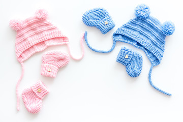 Knitted blue and pink footwear and hat for baby on white background top view mockup