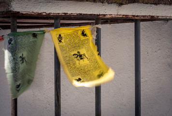 Shabby green and yellow flags with pictures and writings hanging on balcony grate of old building on town street