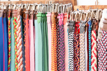 Bunch of assorted multicolored belts hanging on rack on market stall