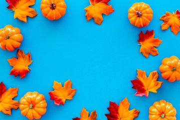 Autumn background with leaves and pumpkins on blue top view space for text frame