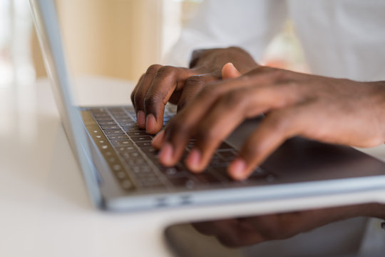 Close up of african business man hands working using keyboard of computer laptop