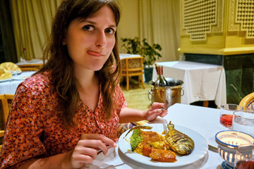 Young woman eating fish in Arab restaurant, close-up portrait