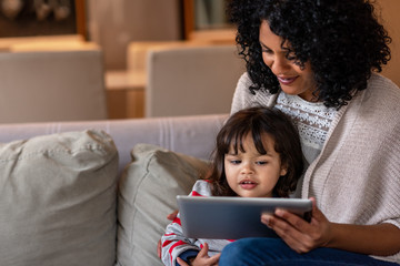 Smiling mother and little daughter using a digital tablet together