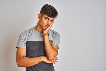 Young indian man wearing casual t-shirt standing over isolated white background thinking looking tired and bored with depression problems with crossed arms.