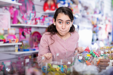 Emotional small girl choosing sweet candies in the candy shop