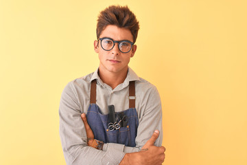 Young handsome hairdresser man wearing apron and glasses over isolated yellow background skeptic...