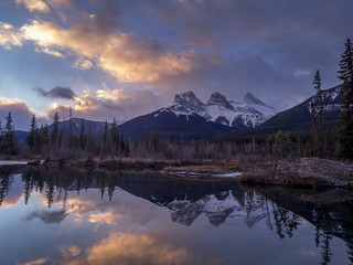 Sunrise view of Policeman`s Creek along the Bow River outside Canmore, Alberta in winter. Pictured is the famous mountain known as the Three Sisters.