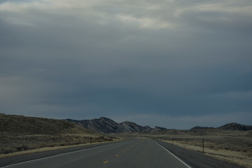 Rural road and dark cloudy sky in Wyoming, USA