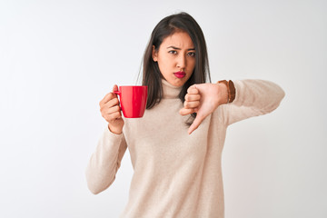 Beautiful chinese woman drinking red cup of coffee standing over isolated white background with...