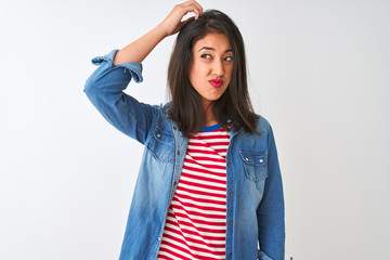 Young chinese woman wearing striped t-shirt and denim shirt over isolated white background confuse and wondering about question. Uncertain with doubt, thinking with hand on head. Pensive concept.