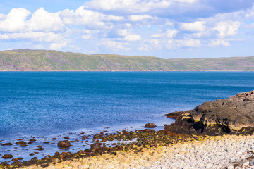 White stone beach near Teriberka, Murmansk, Russia. Round white stones are washed by azure waters of the Barents sea (Arctic ocean)