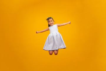 Beautiful asian girl sitting on yellow background. Happy little Asian girl smiling.