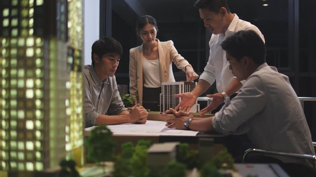 Asian manager and Business people meeting with paper blueprint and building model. Engineering management performance and engineer meeting share ideas concept.