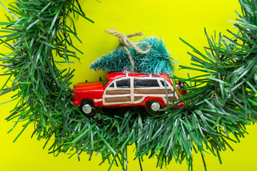 Christmas Tree on a toy car on bright yellow background. Winter Holidays celebration concept.