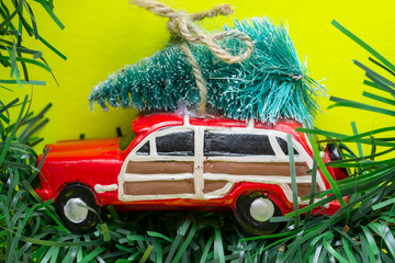 Christmas Tree on a toy car on bright yellow background. Winter Holidays celebration concept.