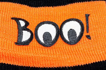 Boo! - Holiday decoration on bright orange material background. Halloween celebration concept.