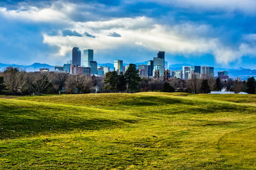 Fototapeta na wymiar Clouds Gather over Denver Skyline in the Evening - Grassy Field in Foreground