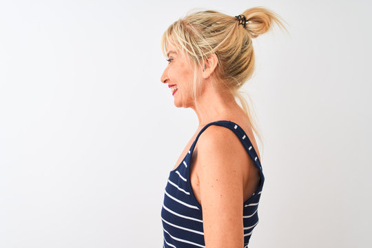 Middle age woman wearing casual striped t-shirt standing over isolated white background looking to side, relax profile pose with natural face with confident smile.
