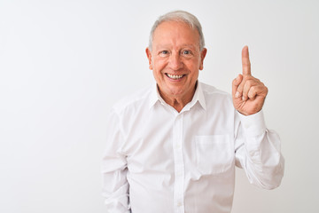 Senior grey-haired man wearing elegant shirt standing over isolated white background pointing finger up with successful idea. Exited and happy. Number one.