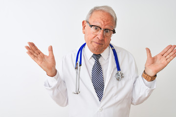 Senior grey-haired doctor man wearing stethoscope standing over isolated white background clueless and confused expression with arms and hands raised. Doubt concept.