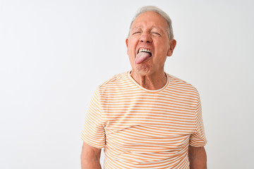 Obraz premium Senior grey-haired man wearing striped t-shirt standing over isolated white background sticking tongue out happy with funny expression. Emotion concept.