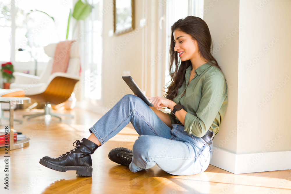 Wall mural Beautiful young woman working using touchpad tablet sitting on the floor