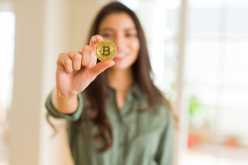 Young woman smiling holding bitcoin cryptocurrency as electronic payment