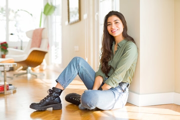 Young beautiful woman sitting on the floor at home with a happy and cool smile on face. Lucky person.