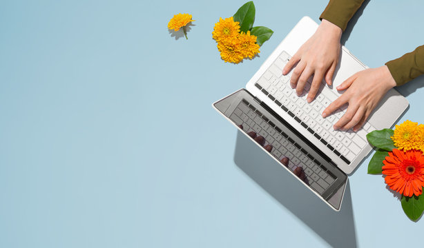 Person using a laptop computer with autumn flowers - overhead view
