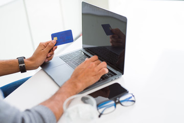 Fototapeta premium Man using credit card as payment metod when shopping online using laptop, blank screen concept