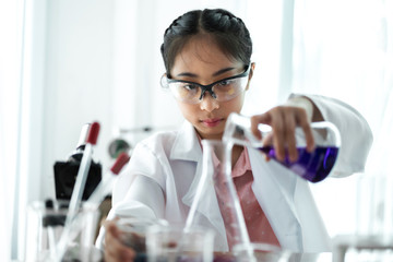 Teenage girl students learning and doing a chemical experiment and holding test tube in hands in science class on the table.Education concept