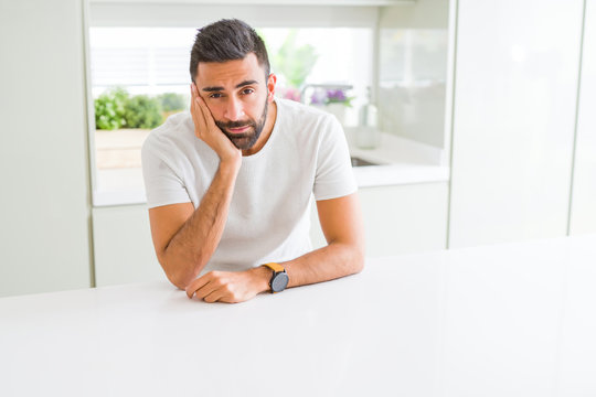 Handsome hispanic man casual white t-shirt at home thinking looking tired and bored with depression problems with crossed arms.