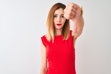 Redhead businesswoman wearing elegant red dress standing over isolated white background looking unhappy and angry showing rejection and negative with thumbs down gesture. Bad expression.