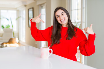 Beautiful young woman drinking a cup of black coffee looking confident with smile on face, pointing oneself with fingers proud and happy.