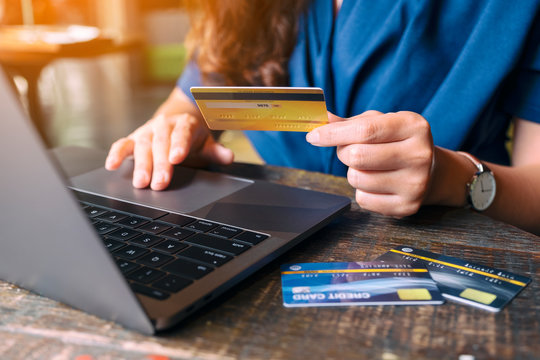 Closeup image of a business woman holding credit cards while using laptop computer