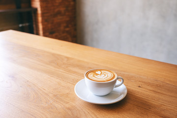 A white mug of hot latte coffee on wooden table
