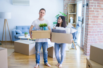 Fototapeta na wymiar Young beautiful couple moving cardboard boxes at new home