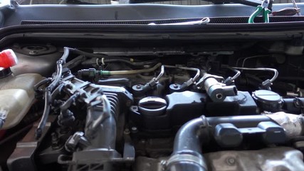 Dolly shot of car's engine exposed in an auto shop.