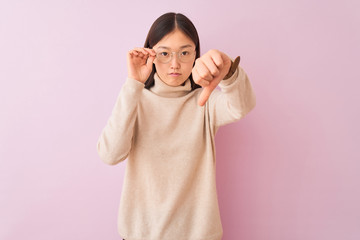 Young chinese woman wearing turtleneck sweater and glasses over isolated pink background with angry...