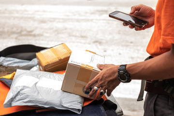 Young modern delivery man using smartphone on delivery box package in working time.