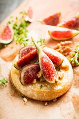Baked camembert cheese with figs, walnuts, honey and thyme on the rustc background. Selective focus. Shallow depth of field.
