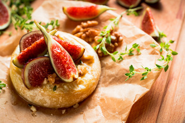 Baked camembert cheese with figs, walnuts, honey and thyme on the rustc background. Selective focus. Shallow depth of field.