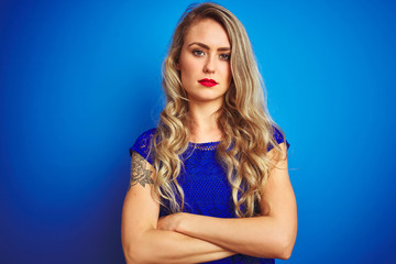 Young beautiful woman standing over blue isolated background skeptic and nervous, disapproving...